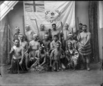 Maori men standing in front of the Moutoa flag