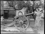 Unidentified woman standing beside a Kinman cannon at Britomart Reserve, Akaroa