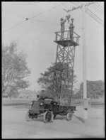Two men on a cherry-picker [attaching a street lamp?] on the back of an electric truck, Christchurch City Council Electric No.2 written on side of truck