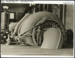 Creator unknown: Photograph of man beside turbo-generators in a Waikaremoana hydro-electric power station, Hawke's Bay