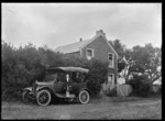 A car with four people parked outside a two storied house at Kaitoke, 1923