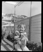 Boy on rocking horse in garden of Dr Harvey, 14 Churchill Drive, Wellington
