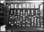 Museum display cabinet with combs, eardrops, hei tiki and other items