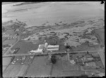 View of Woollen Mills factory buildings with the Manukau Harbour tidal flats beyond, Onehunga, South Auckland