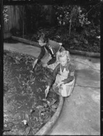 Girl Guide, and a Brownie, working in a garden during Bob a Job Week
