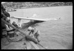 Men in dinghy attaching a Royal New Zealand Air Force Catalina flying boat to hoist, Evans Bay, Wellington