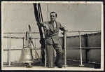 Merton Hodge standing next to a bell on board the Queen Mary