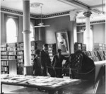 General Assembly Library, Wellington, with the Librarian James Oakley Wilson showing the first Speaker's chair to two Indonesian students