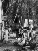 Scene outside a house, including a woman at a sewing machine, a child, and geese, Buller region