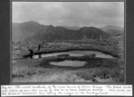 The second crossing of the Tararua Range from Levin to Masterton, Feb 9-17, 1911. The most northerly of the nine tarns of Tarn Ridge. The piled rocks are relics of our old camp of Feb 16-17, 1909. Our route on the present occasion lay along the ridges in the background.