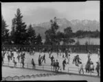 Crowd at skating rink, Queenstown with Lake Wakatipu and The Remarkables in the background