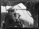 Captain looking through a sextant [?] in the seaplane Aotearoa in Suva, Fiji survey flight