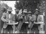 Group of Maori men eating watermelon, location unidentified