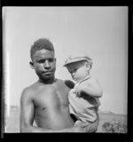 Local Lae person holding 14 month old John Loney, Lae airfield, Papua New Guinea