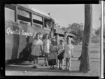 Group of unidentified Berrimah children are going to school, standing next to Qantas Empire Airways bus, Darwin, Australia
