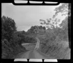 View of dirt road through the countryside, with a horse and rider and bure in the distance, Ba, Fiji