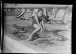 Qantas Empire Airways, young girl sitting on the back of an imitation crocodile by the side of a swimming pool, Berrimah, Darwin, Australia