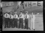 Qantas Empire Airways crew stand in front of a Douglas DC-4 (VH-EBK) Skymaster aircraft at Kai-Tak Airport, Kowloon, Hong Kong, including Captain Hampshire (wearing the black cap) and Neil Geikie on the far right