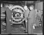 Sir Miles Thomas, Chairman of British Overseas Airways Corporation, looking at an aircraft engine with unidentified Tasman Empire Airways Limited and BOAC employees