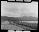 Unidentified man and Morris Minor beside Lake Manapouri, Southland district