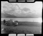 Unidentified man and Morris Minor beside Lake Manapouri, Southland district