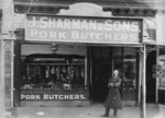 Man standing outside the premises of J Sharman and Sons, pork butcher, Christchurch