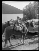 Lake Paringa, South Westland, shows boy on horse with another horse alongside