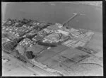 Close-up view over the New Zealand Refrigerating Company, Imlay Freezing Works Imlay Place, Wanganui, with stock pens and yards, and effluent treatment ponds, and stacks of timber next to residential housing with Balgownie Avenue and Wordsworth Street, located beside the Wanganui River with wharf for loading ships