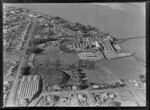 View over the New Zealand Refrigerating Company, Imlay Freezing Works Imlay Place, Wanganui, with stock pens and yards, showing Heads Road, Balgownie Avenue and Beach Road surrounded by residential housing, located beside the Wanganui River with wharf for loading ships