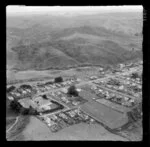 Pukemiro, near Huntly, Waikato, showing coal mining area, view to residential housing area on hill top with Pukemiro Primary School and sports field next to John Avenue and Joseph Street, with Rotowaro Road in the valley and bush covered hills beyond