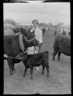 An unidentified woman with a prize-winning cow and calf at the Wairarapa Agricultural and Pastoral show, Carterton