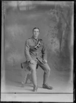 Studio portrait of an unidentified World War I soldier with bandolier ammunition belt over left shoulder, collar badges and stirrups [Mounted Rifles?], Christchurch