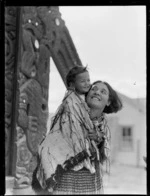 Unidentified Maori mother and baby, outside a marae (meeting house)