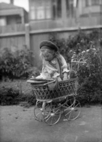 Doreen Gifford playing with her pram in a garden