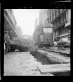 Loaded truck stuck in a ditch in Willis Street, Wellington, tram passing alongside