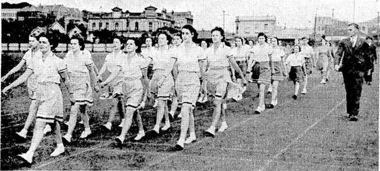 Image: Eyeulng Post" Photo. Girls at the Basin Reserve this morning practising for the inter-house marching contest lo be held on Wednesday evening. They are being trained by Mr. C. McCalman (right), physical ivelfare officer of the Department of Internal Affairs. (Evening Post, 25 February 1941)