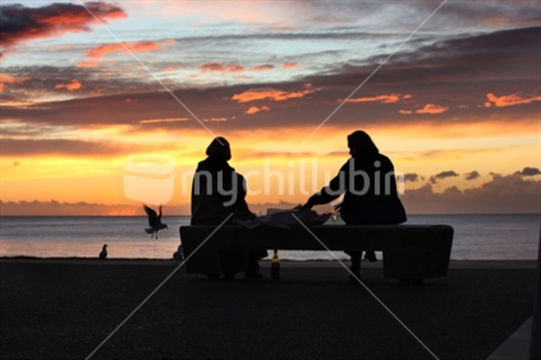 Image: A bottle of wine and fish and chips as the sun sets off New Plymouth