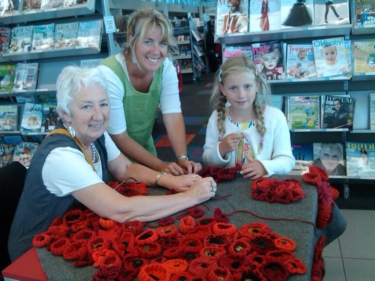 Image: Grandma, Mum and daughter sewing on the poppies they made for the Poppy Blanket project