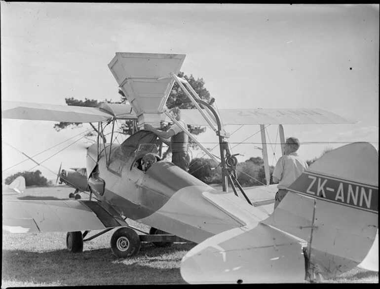 Image: Farmland at Ihumatao, Mangere, Manukau city, Auckland Region, featuring fertiliser being funnelled into an aerial topdressing plane [ZK-ANN Tiger Moth?] by unidentified men