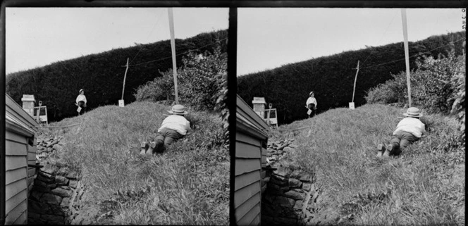 Brothers Edgar Richard and Owen William Williams playing war game in the garden of the Williams' Royal Terrace house, Kew, Dunedin, including British flag and gun