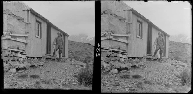 Unidentified man standing beside a hut [along the Routeburn Track?]