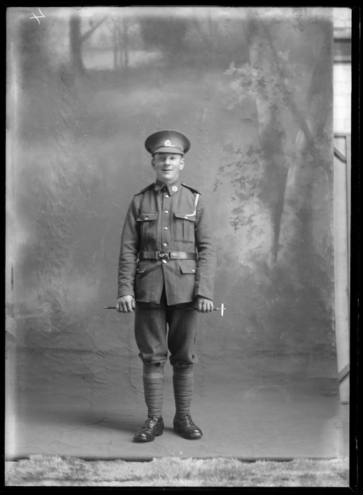 Studio portrait of unidentified soldier in uniform, holding a swagger stick, probably Christchurch district