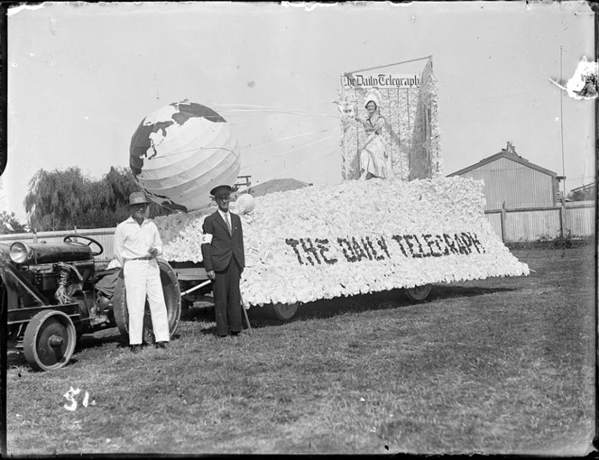 New Napier Week Carnival, men and woman in costumes with 'The Daily Telegraph' float pulled by a tractor, waiting for parade to start, Napier, Hawke's Bay District