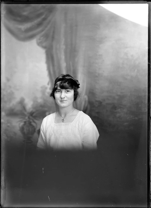 Studio portrait of the upper torso of an unidentified woman wearing a white cotton dress, with a black ribbon in her hair, possibly Christchurch district