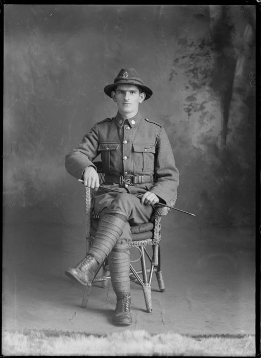 Studio portrait of unidentified soldier, in uniform, holding a swagger stick, probably Christchurch district