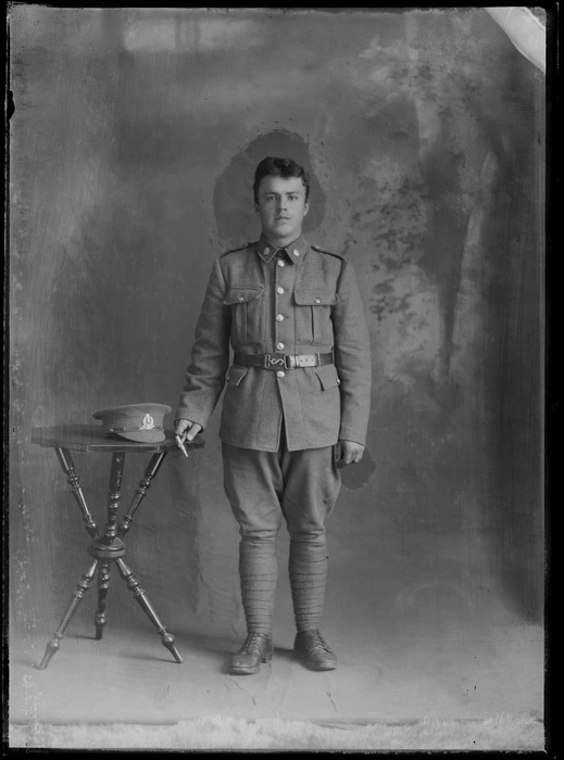 Studio unidentified portrait of a young World War I soldier with star collar [Army Service Corps?] and hat [Reinforcements?] badges, swagger stick, and black shoulder webbing, Christchurch
