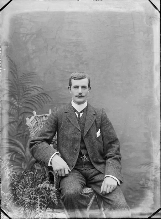 Studio unidentified portrait of a man with moustache, three piece woollen suit, imperial shirt collar and greenstone watch chain pendant, sitting in a chair, Christchurch