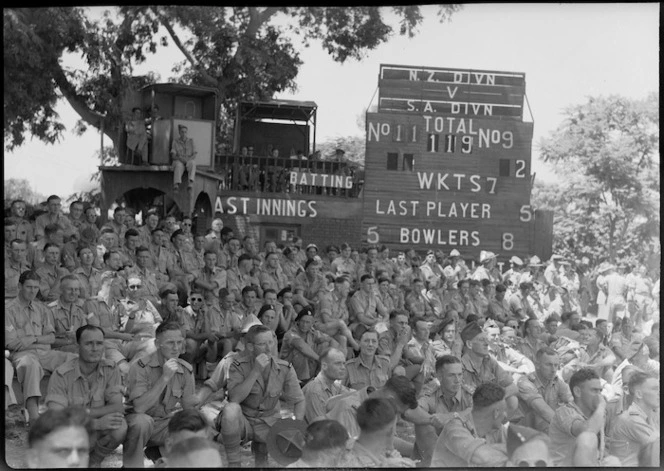 Spectators taking advantage of shade near scoreboard at cricket match in Gazira, Cairo - Photograph taken by G Kaye