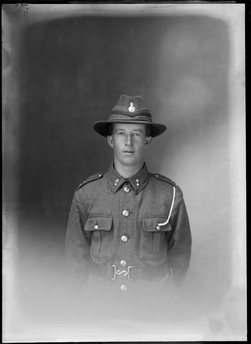 Studio upper torso portrait of an unidentified young WWI soldier with collar and hat badges, and white shoulder cord attached to his left pocket, Christchurch