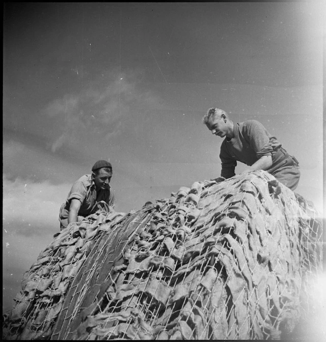 New Zealanders adjust the camouflage netting on their truck just behind the line in Italy, World War II - Photograph taken by George Kaye